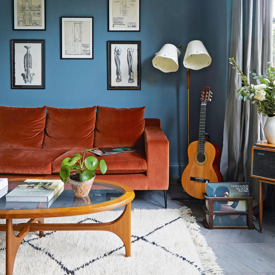 navy living room with burnt orange sofa, white berber rug and glass topped coffee table