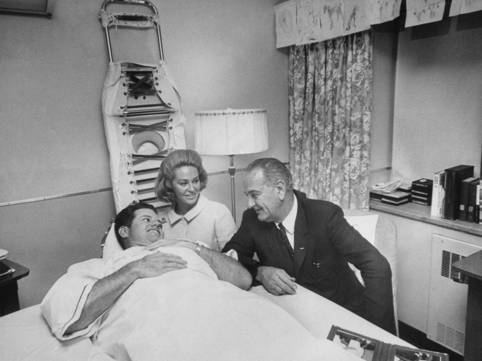 Sen. Edward Kennedy, lying in a hospital bed, is visited by President Lyndon B. Johnson in the hospital