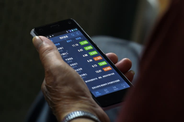An investor checks stock prices on his smart phone at a securities company in Beijing on July 9, 2015