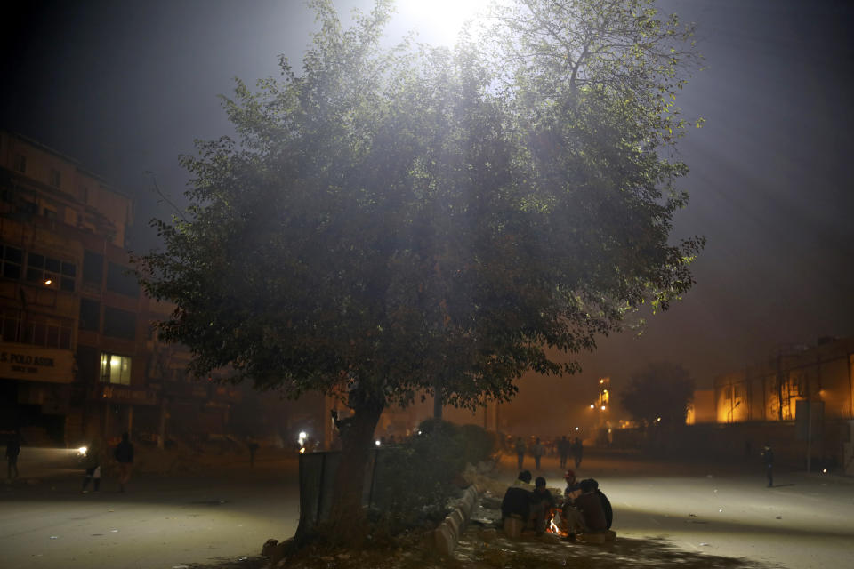 In this Tuesday, Jan. 21, 2020 photo, volunteers keep themselves warm around a bonfire as they man a check-point near the protest site in New Delhi's Shaheen Bagh area, India. Muslim women are transcending the confines of their homes to lay claim to the streets of this nondescript Muslim neighborhood in the Indian capital and slowly transforming it into a nerve center of resistance against a new citizenship law that has unleashed protests across the country. The gathering at Shaheen Bagh started with a handful of women appalled by the violence at a nearby Muslim university during protests against the law on Dec. 15. Since then it has slowly morphed into a nationwide movement, with many women across the country staging their own sit-ins. (AP Photo/Altaf Qadri)