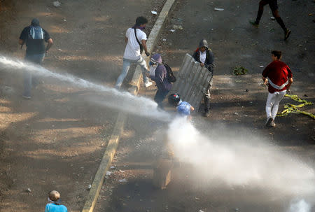 A demonstrator is being sprayed with water during clashes with security forces following a rally against the government of Venezuela's President Nicolas Maduro and to commemorate May Day in Caracas Venezuela, May 1, 2019. REUTERS/Adriana Loureiro