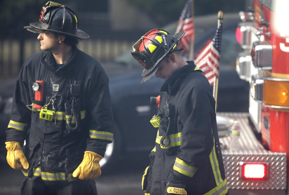 ADDS LAST SENTENCE - A firefighter, right, lowers his head at the scene of a multi-alarm fire at a four-story brownstone in the Back Bay neighborhood near the Charles River, Wednesday, March 26, 2014, in Boston. A Boston city councilor said two firefighters have died in a fire that ripped through a brownstone. (AP Photo/Steven Senne)