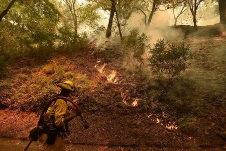 A firefighter passes flames from the Soberanes Fire as it burns the Rancho San Carlos community of Carmel-by-the-Sea, California, U.S. July 27, 2016. REUTERS/Noah Berger