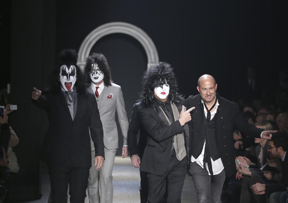 American fashion designer John Varvatos, right, is accompanied by Rock Band Kiss as he acknowledges the applause of the audience, at the end of his men's Autumn-Winter 2014 collection, part of the Milan Fashion Week, unveiled in Milan, Italy, Saturday, Jan. 11, 2014. (AP Photo/Antonio Calanni)