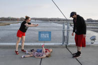 In this April 6, 2020 photo, a family on the Bob Kerrey pedestrian bridge over the Missouri River take a photo of their children lying over the imaginary line between Omaha, Neb., and Council Bluffs, Iowa. As most governors have imposed stay-at-home orders that public health officials say are essential to slowing the spread of the new coronavirus, leaders in a handful of states have steadfastly refused to take the action, arguing it's unneeded and potentially harmful. (AP Photo/Nati Harnik)