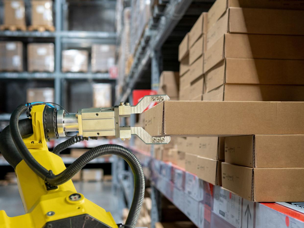 yellow robotic arm carry cardboard box in warehouse