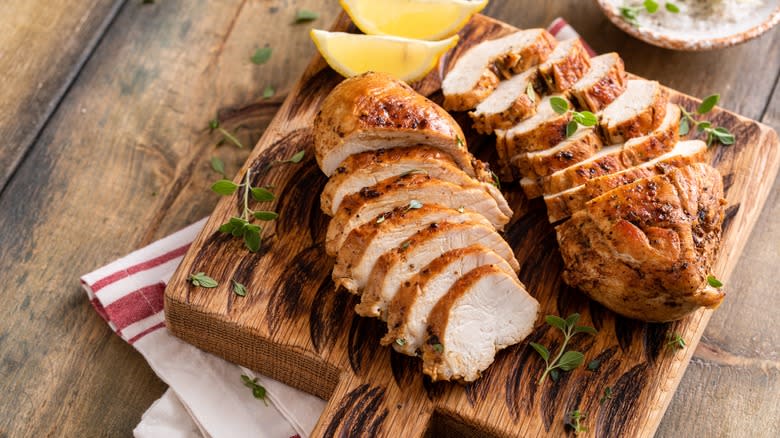 Sliced chicken breasts on wooden board