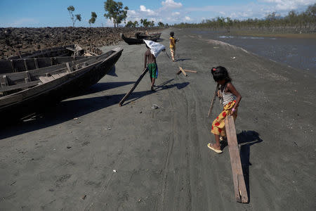 Children collect wood from remnants of some 20 boats that ferried Rohingya refugees fleeing violence in Myanmar, which were destroyed by Bangladeshi authorities the night before, at Shah Porir Dwip near Cox's Bazar, Bangladesh October 4, 2017. REUTERS/Damir Sagolj