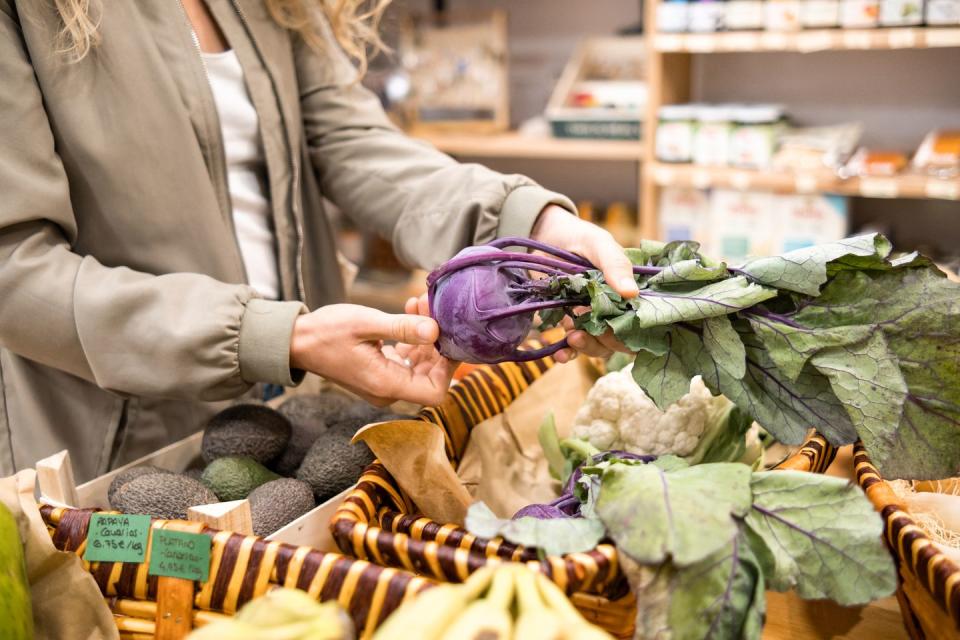 unrecognizable woman buying kohlrabi vegetables at local organic grocery store