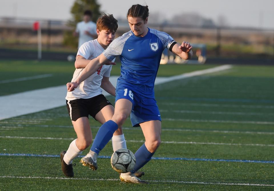 Bondurant-Farrar's Evan Reha (18) clears the ball around Gilbert's Owen Wirth (4) during the first half at Bondurant Farrar High School, April 26, 2022, in Bondurant, Iowa.