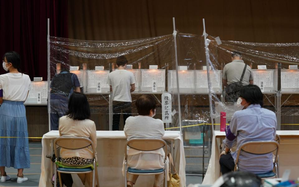 Election officials observe from behind a vinyl screen at a polling station in Tokyo - KIMIMASA MAYAMA/EPA-EFE/Shutterstock