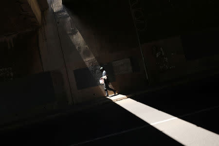 A man carries a bucket used to collect water from a small roadside spring in Cape Town, South Africa, February 4, 2018. REUTERS/Mike Hutchings