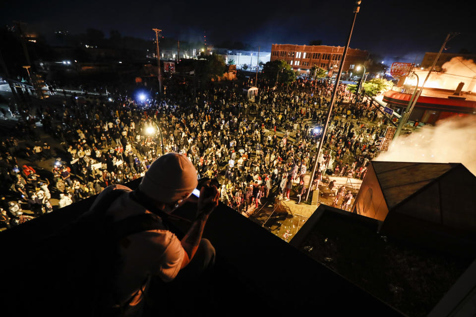 Protestors demonstrate outside of a burning Minneapolis 3rd Police Precinct, Thursday, May 28, 2020, in Minneapolis. Protests over the death of George Floyd, a black man who died in police custody Monday, broke out in Minneapolis for a third straight night. (AP Photo/John Minchillo)