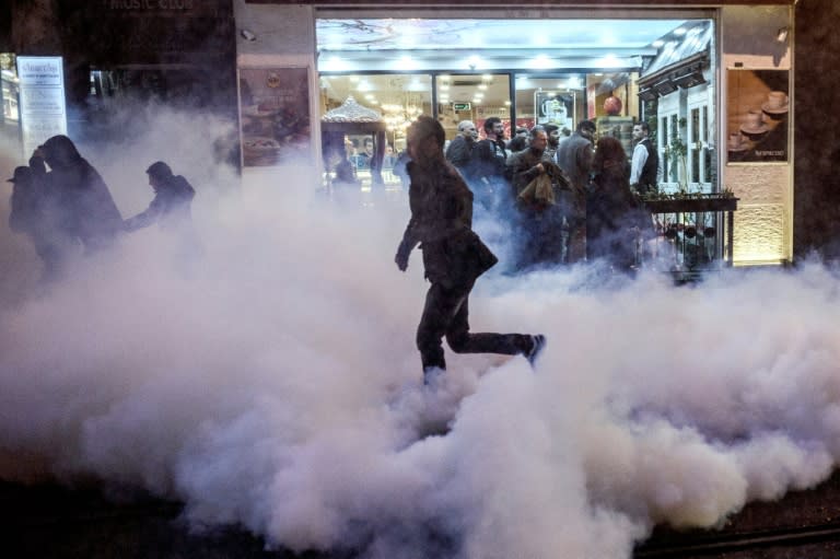 A protester runs for cover from tear gas fired by Turkish riot police to disperse protesters during a demonstration after a top Kurdish lawyer was killed in Diyarbakir on November 28, 2015