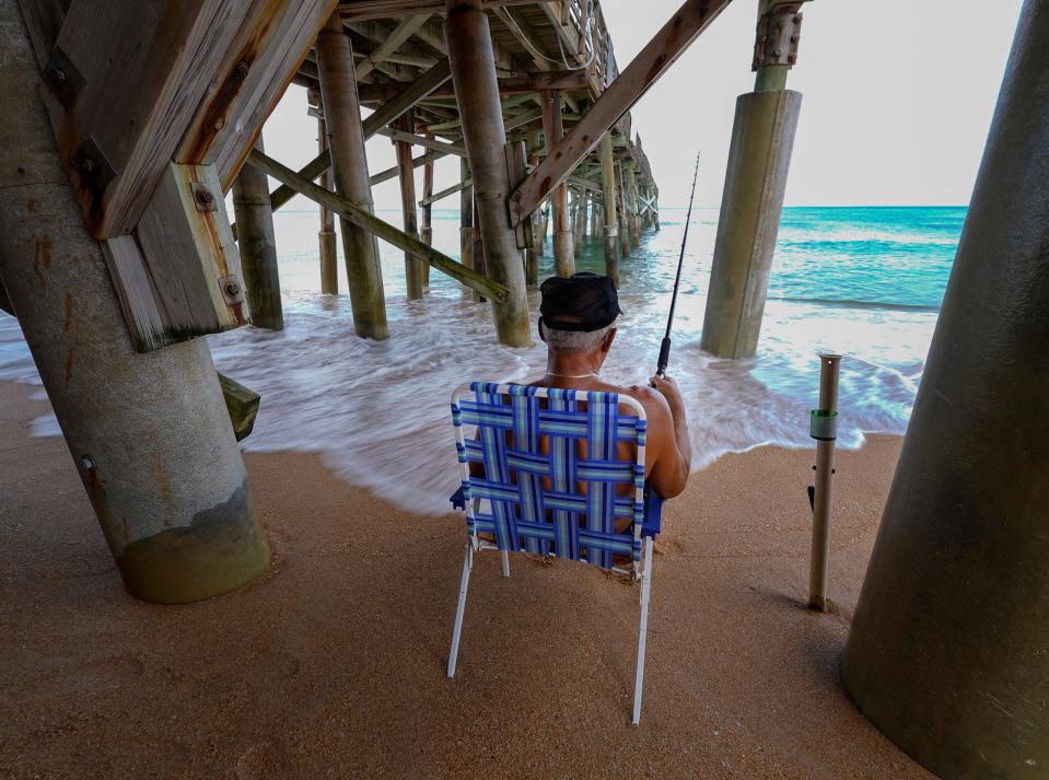 A man fishes underneath the Flagler Beach pier, Tuesday, Aug. 8, 2023. The pier has been closed since sustaining damage during Tropical Storms Ian and Nicole.