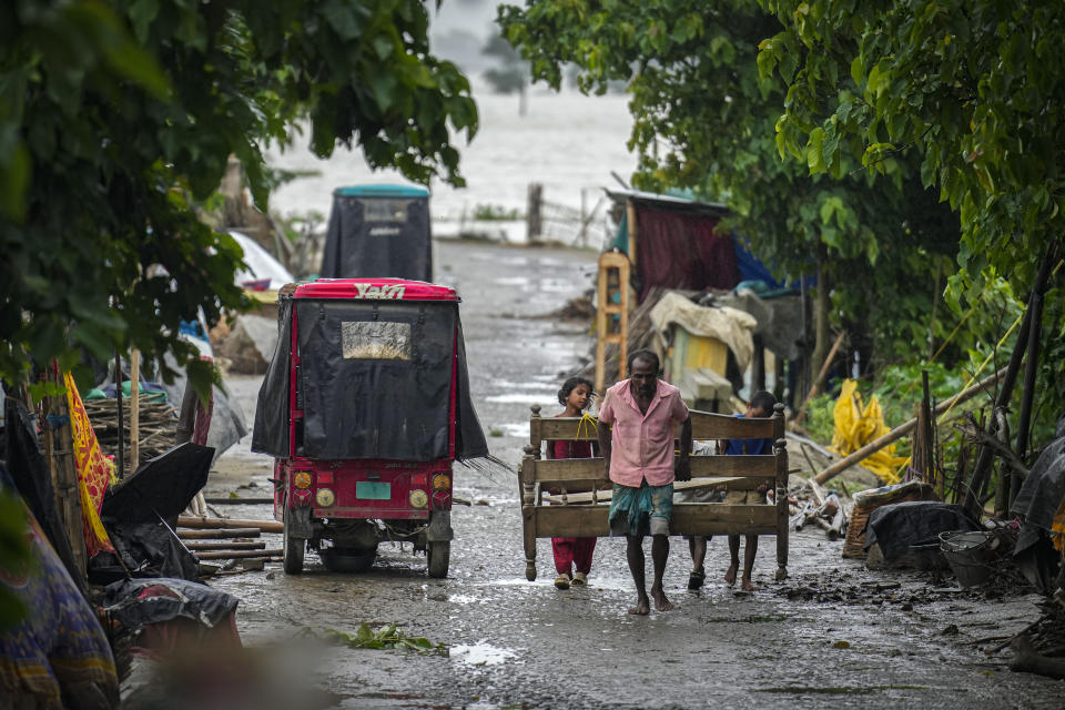 A flood affected man and his children carry a bed to a higher ground in Sildubi village in Morigaon district in the northeastern state of Assam, India, Tuesday, July 2, 2024. Floods and landslides triggered by heavy rains have killed more than a dozen people over the last two weeks in India's northeast. (AP photo/Anupam Nath)