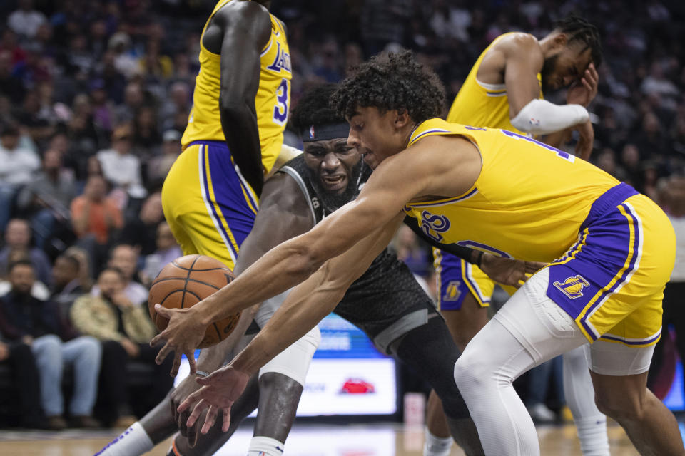 Sacramento Kings center Neemias Queta and Los Angeles Lakers guard Max Christie, right, scramble for the ball during the first half of an NBA basketball game in Sacramento, Calif., Wednesday, Dec. 21, 2022. (AP Photo/José Luis Villegas)