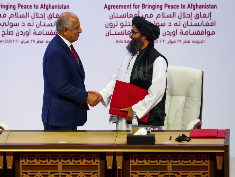 Mullah Abdul Ghani Baradar, the leader of the Taliban delegation, and Zalmay Khalilzad, U.S. envoy for peace in Afghanistan, shake hands after signing an agreement at a ceremony between members of Afghanistan's Taliban and the U.S. in Doha