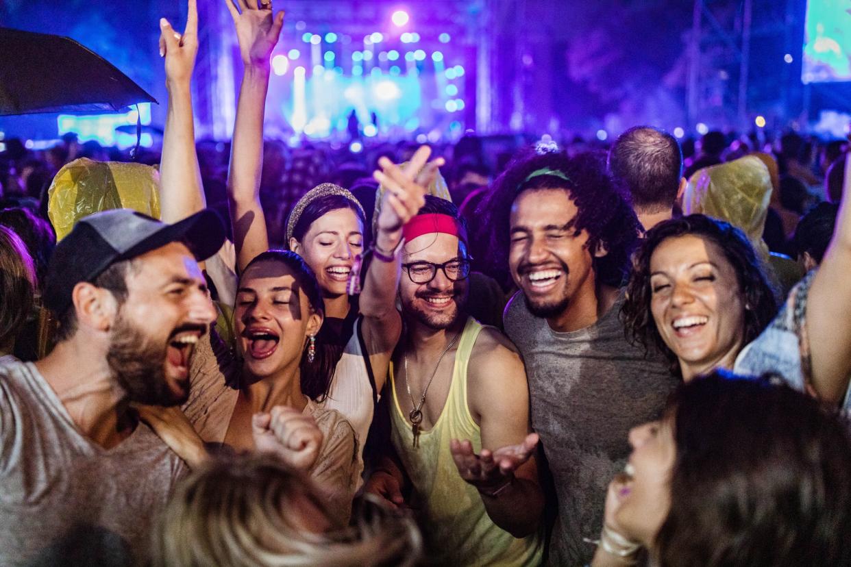 Large group of cheerful friends having fun on music festival by night.