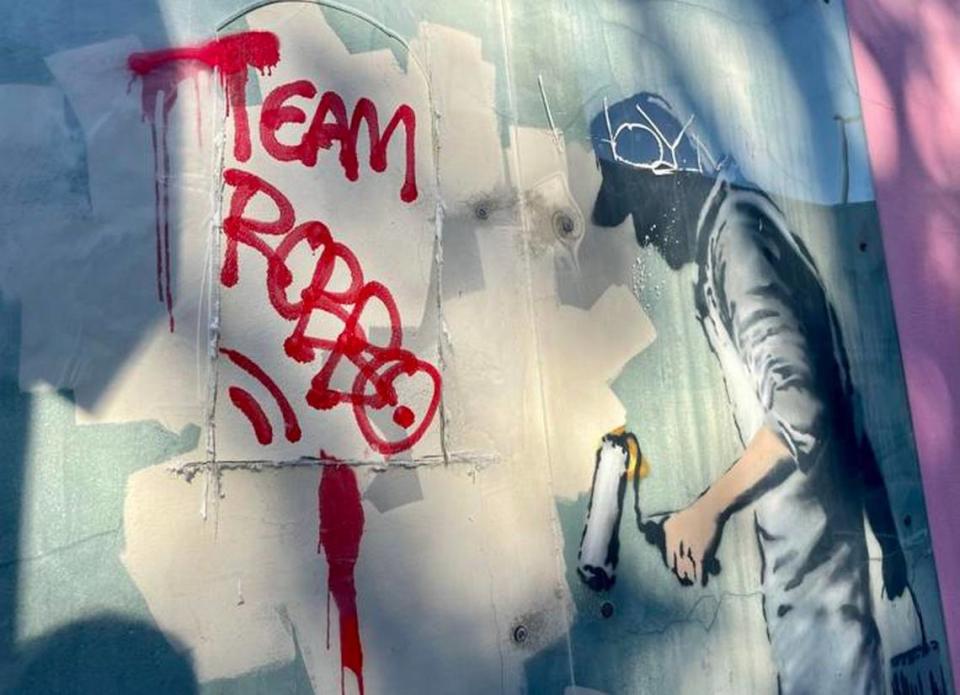 Taggers cut through a plastic barrier to deface a 2008 painting by street art superstar Banksy. 