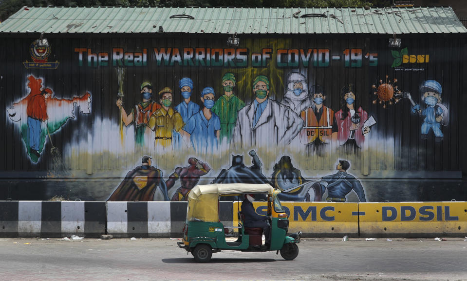 An auto rickshaw drives past a mural depicting frontline workers fighting against COVID-19 in New Delhi, India, Tuesday, Sept. 1, 2020. India has now reported more than 75,000 infections for five straight days, one of the highest in the world, just as the government began easing restrictions to help the battered economy. (AP Photo/Manish Swarup)