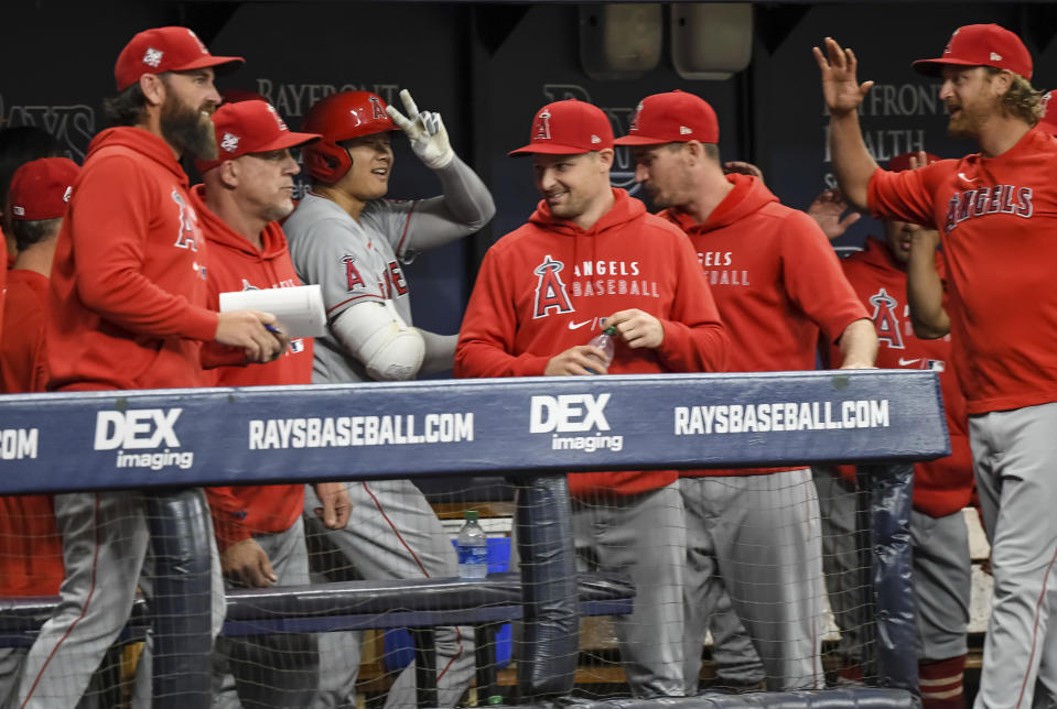 Los Angeles Angels teammates congratulate Shohei Ohtani, center, in the dugout after his solo home run during the first inning of a baseball game against the Tampa Bay Rays, Friday, June 25, 2021, in St. Petersburg, Fla. (AP Photo/Steve Nesius)