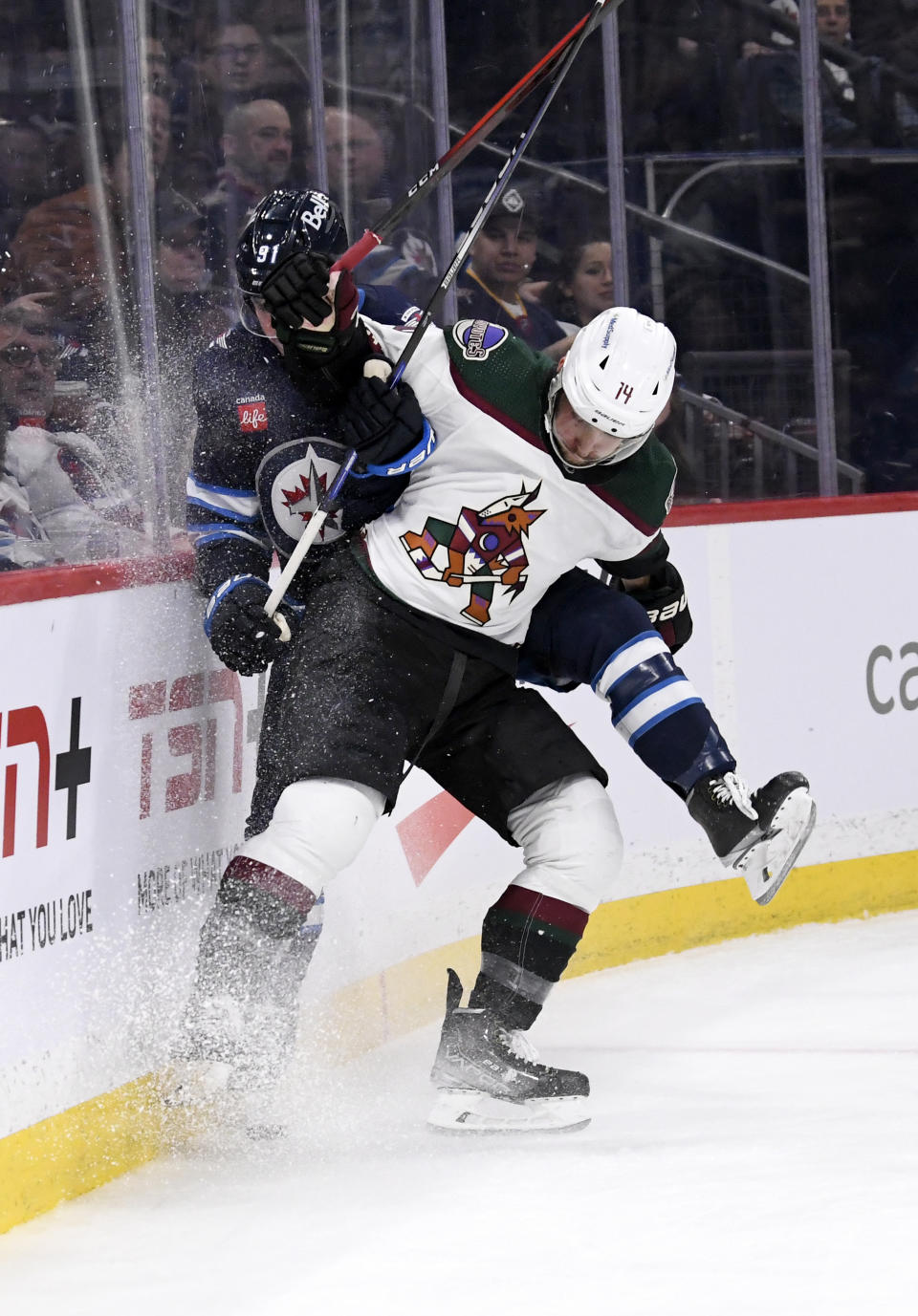 Arizona Coyotes defenseman Shayne Gostisbehere (14) checks Winnipeg Jets center Cole Perfetti (91) during second-period NHL hockey game action in Winnipeg, Manitoba, Sunday, Jan. 15, 2023. (Fred Greenslade/The Canadian Press via AP)