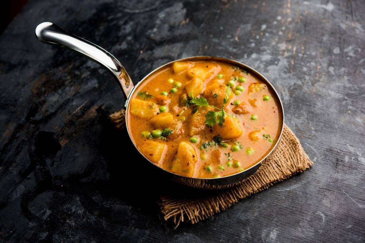 Indian Aloo Mutter curry - Potato and Peas immersed in an Onion Tomato Gravy and garnished with coriander leaves. Served in a Karahi/kadhai or pan or bowl. selective focus