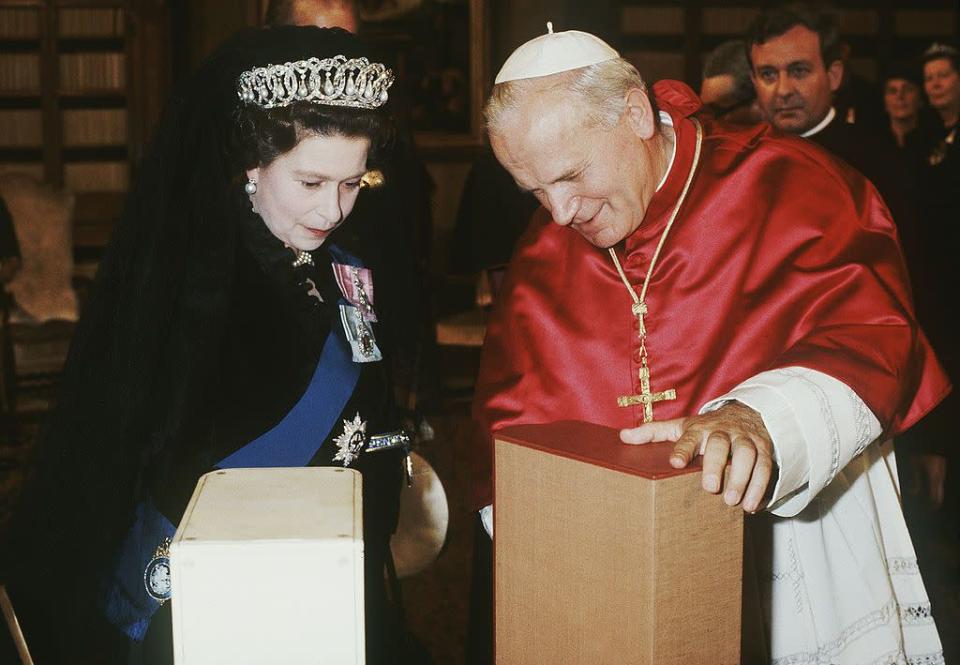 <p>Her Majesty is seen with the Pope at the time, John Paul II. They appear deep in thought while exchanging gifts.</p>