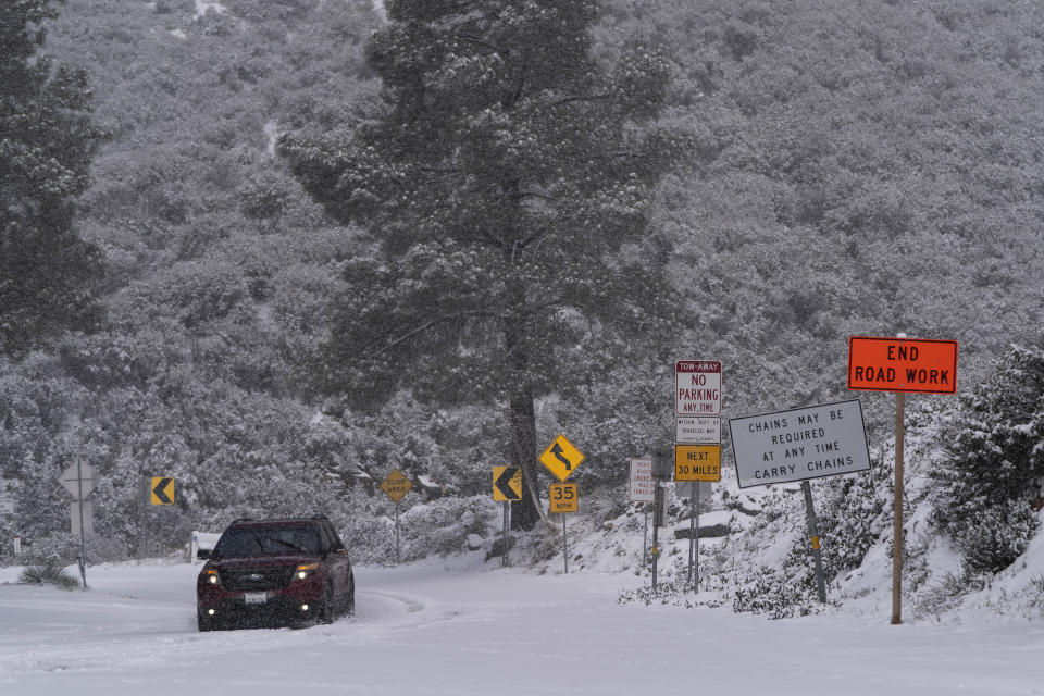 A motorist drives along a snow-covered road in the Angeles National Forest near La Canada Flintridge, Calif., Thursday, Feb. 23, 2023. For the first time since 1989, the National Weather Service issued a blizzard warning for the Southern California mountains. (AP Photo/Jae C. Hong)