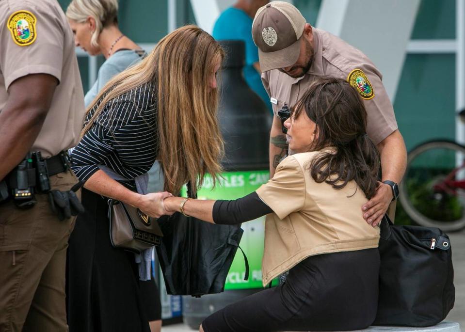 A woman is comforted by a police officer and another person at the Surfside Community Center, where family and friends of those listed missing waited for news about their loved ones in Surfside on June 25, 2021.