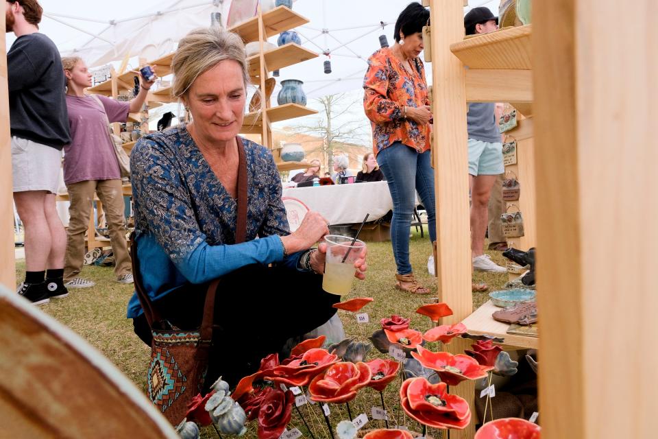 Vicki McInnally looks at crafted flowers in the Kentuck Art Center Red Dog Potter display at the Druid City Arts Festival on March 31, 2023, in Government Plaza.