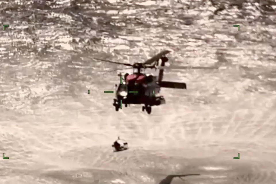 In this screenshot from video, the U.S. Coast Guard rescues boaters off the coast of Empire, La., on Sunday, Oct. 9, 2022. Three men whose fishing boat sank in the Gulf of Mexico off the Louisiana coast were rescued after surviving for more than a day despite being attacked by sharks that inflicted deep cuts on their hands and shredded one of their life jackets, according to their rescuers. (U.S. Coast Guard via AP)