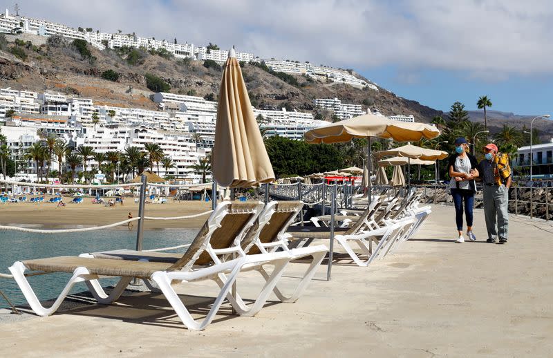 Two tourists walk near Puerto Rico beach, in Gran Canaria