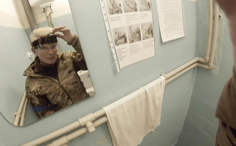 FILE - Yuliia Paievska, known as Taira, looks in a mirror and turns off her camera in Mariupol, Ukraine, on Feb. 27, 2022. The celebrated Ukrainian medic, who used the body camera to record her work in Mariupol while the port city was under Russian siege, was later captured by Russian troops. Ukrainian President Volodymyr Zelenskyy announced Friday, June 17, 2022, that Russia has freed Paievska. (Yuliia Paievska via AP)