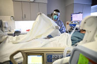 FILE - In this Monday, Dec. 7, 2020 file phto, Marie Pelkey, a critical care nurse at North Memorial Health Hospital in Robbinsdale, Minn., drapes a warm blanket over a COVID-19 patient who was just admitted into the South Seven Intensive Care Unit after their condition worsened. (Aaron Lavinsky/Star Tribune via AP)
