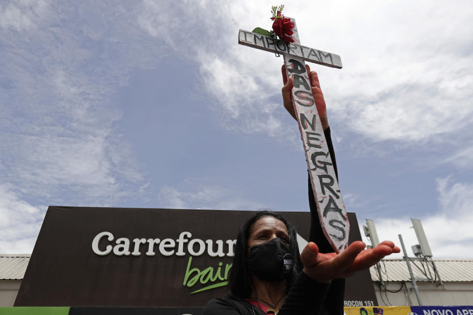 Holding a cross covered with the Portuguese message "Black Lives Matter," a person demonstrates against the murder of Black man João Alberto Silveira Freitas, which occurred the night before at a different Carrefour supermarket, on Brazil's National Black Consciousness Day in Brasilia, Brazil, Friday, Nov. 20, 2020. Freitas died after being beaten by supermarket security guards in the southern Brazilian city of Porto Alegre, sparking outrage as videos of the incident circulated on social media. (AP Photo/Eraldo Peres)