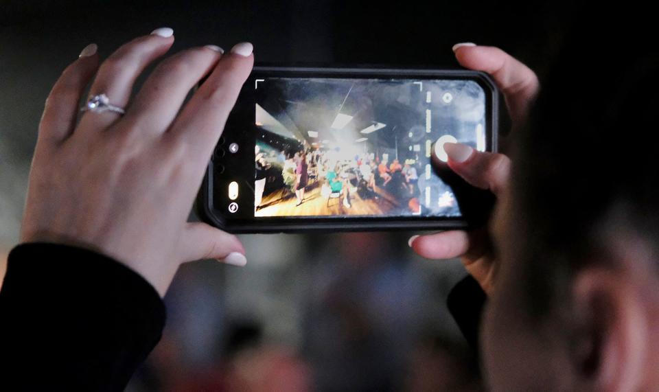 A woman takes a picture of the large crowd during a town hall meeting explaining some preliminary downtown density proposals.