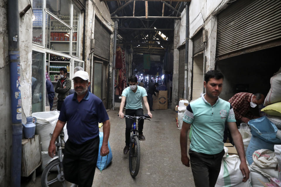 A man rides his bicycle as the others walk through the Qazvin old traditional bazaar some 93 miles (150 kilometers) northwest of the capital Tehran Iran, Wednesday, April 22, 2020. Iran's Revolutionary Guard said it put the Islamic Republic's first military satellite into orbit, dramatically unveiling what experts described as a secret space program with a surprise launch Wednesday that came amid wider tensions with the United States. (AP Photo/Vahid Salemi)