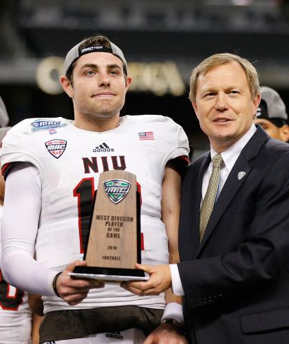 DETROIT, MI - DECEMBER 5: Drew Hare #12 of the Northern Illinois Huskies was awarded the MVP Trophy by the Mid-American Conference Commissioner Dr. Jon Steinbrecher at Ford Field on December 5, 2014 in Detroit, Michigan. The Huskies defeated the Falcons 51-17. (Photo by Leon Halip/Getty Images)