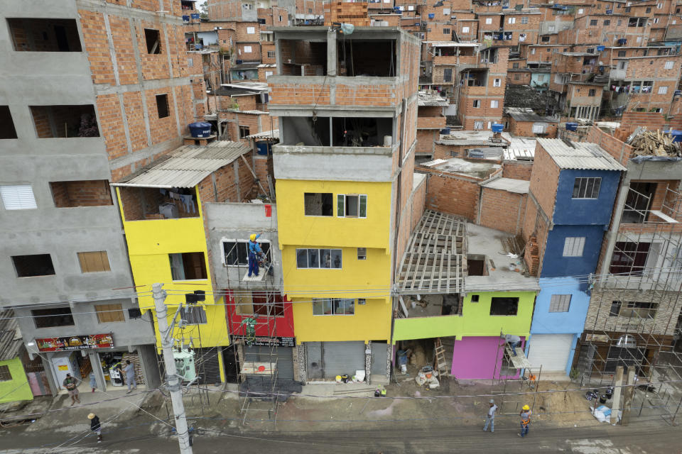 Workers paint the facades of residences in the Paraisopolis favela, as part of the community's centennial celebration, in Sao Paulo, Brazil, Thursday, Sept. 16, 2021. One of the largest favela's in Brazil, home to tens of thousands of residents in the country's largest and wealthiest city, Paraisopolis is grappling with crime and a pandemic that have challenged daily life for many who live there, but organizers say its people have built a vibrant community and are launching a 10-day celebration of its achievements. (AP Photo/Andre Penner)