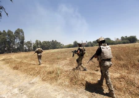 Members of the Iraqi security forces patrol during clashes with fighters from Sunni militant group Islamic State of Iraq and the Levant (ISIL) in Ibrahim bin Ali village, west of Baghdad, June 24, 2014. REUTERS/Ahmed Saad