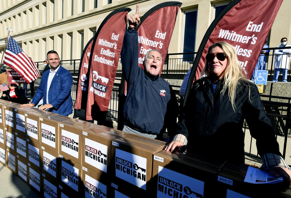 Unlock Michigan Co-Chairs Garrett Soldano, Ron Armstrong and Meshawn Maddock, left to right, speak to supporters in Lansing, Mich., Friday, Oct. 2, 2020. The group on Friday submitted petition signatures in a bid to repeal a law that has given Gov. Gretchen Whitmer broad emergency powers during the coronavirus pandemic, demanding that the veto-proof initiative be put before the Republican-led Legislature before the year's end. It needs roughly 340,000 valid voter signatures for the bill to qualify and has a 200,000 cushion. (Rod Sanford/Detroit News via AP)