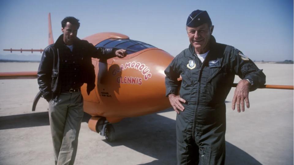 two men stand beside an airplane