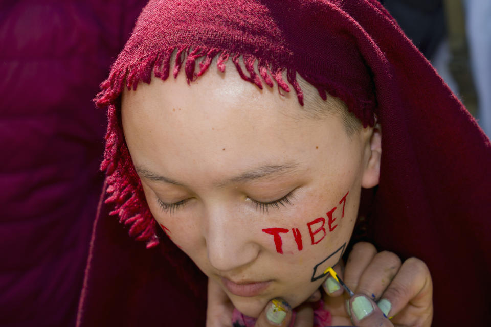 An exile Tibetan Buddhist nun gets a message painted on her cheek before joining in a foot march to commemorate the 1959 uprising in Tibet on this day, in Dharamshala, India, Sunday, March 10, 2024. (AP Photo /Ashwini Bhatia)