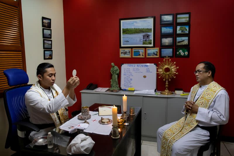 The Wider Image: Hazmat suits and holy water: two priests bring faith to Philippines lockdown