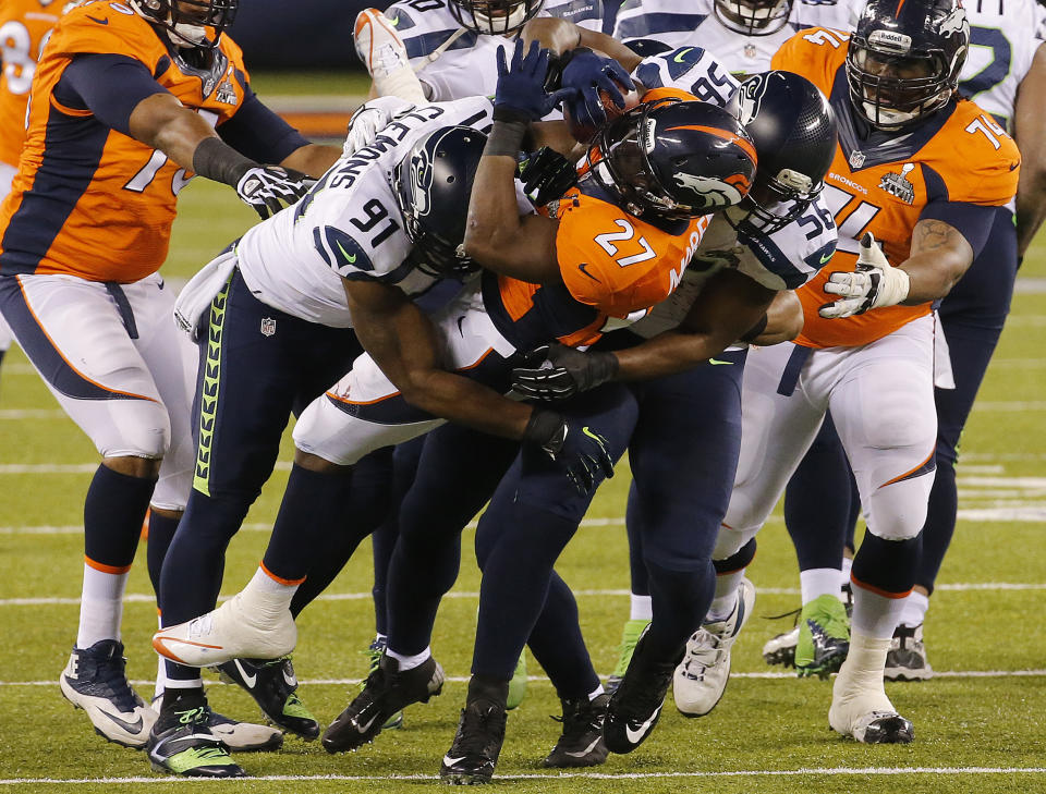 Denver Broncos' Knowshon Moreno (27) is tackled by Seattle Seahawks' Chris Clemons (91) and Cliff Avril (56) during the first half of the NFL Super Bowl XLVIII football game Sunday, Feb. 2, 2014, in East Rutherford, N.J. (AP Photo/Matt York)