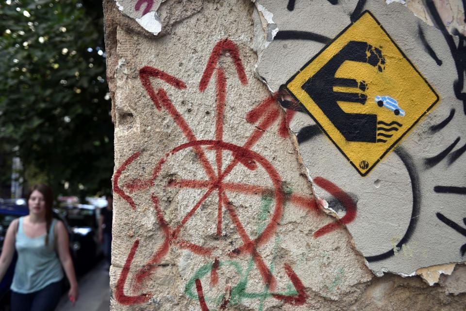 A woman walks past a graffiti by the street artist WD in Athens on June 8, 2015. (LOUISA GOULIAMAKI/AFP/Getty Images)