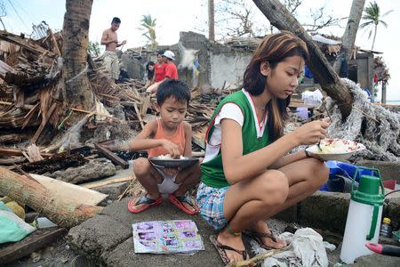 Residents eat outside of their damaged shanties after strong winds and heavy rains brought by typhoon Melor battered Barcelona town, Sorsogon province, central Philippines December 15, 2015. REUTERS/Renelyn Loquinario