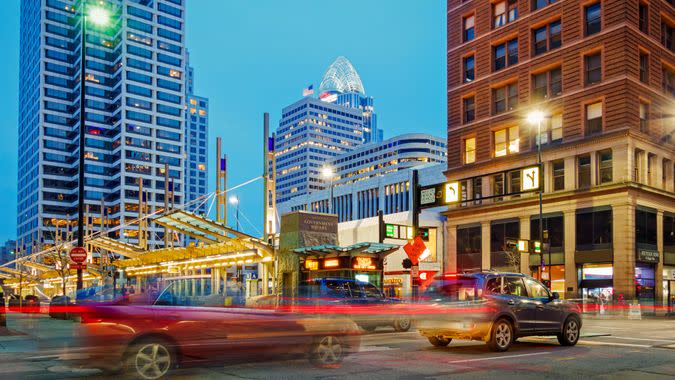 Glimpse of city life with traffic on Walnut Street with office buildings in the background in downtown Cincinnati, Ohio, USA illuminated at twilight.